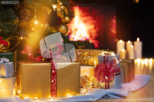 Image of Christmas presents and candles under Christmas tree