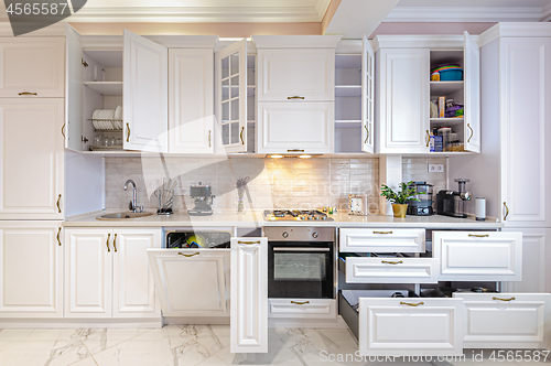 Image of Luxury modern white kitchen interior with open doors and drawers