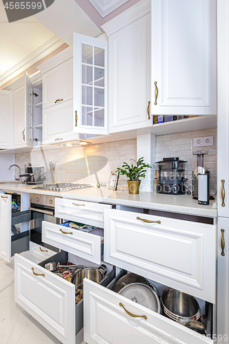 Image of Luxury modern white kitchen interior with open doors and drawers