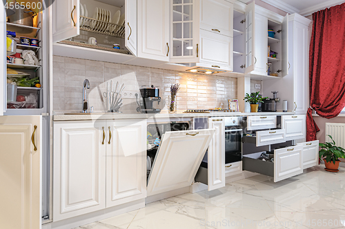 Image of Luxury modern white kitchen interior with open doors and drawers