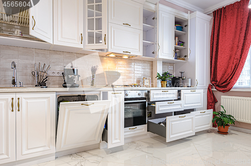 Image of Luxury modern white kitchen interior with open doors and drawers