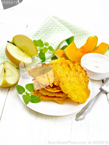 Image of Pancakes of pumpkin with apple in plate on light wooden board