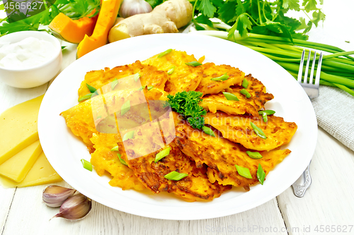 Image of Pancakes of pumpkin with cheese in plate on wooden board