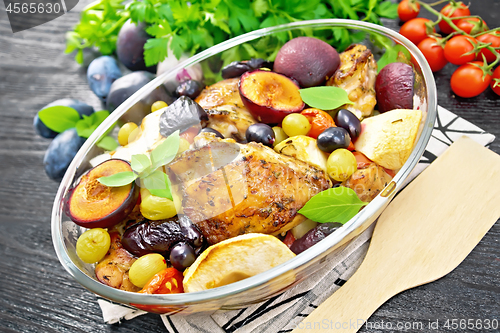 Image of Chicken with fruits and tomatoes in glass pan on wooden board