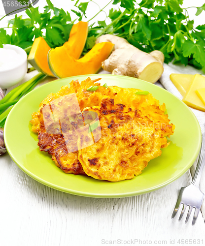 Image of Pancakes of pumpkin with cheese in green plate on light board