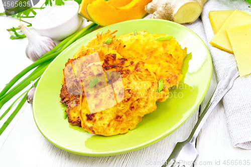 Image of Pancakes of pumpkin with cheese in green plate on white board