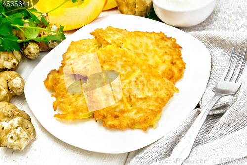 Image of Pancakes of pumpkin with Jerusalem artichoke in plate on light b