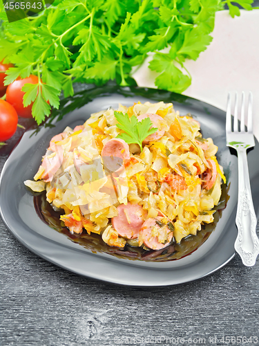 Image of Cabbage stew with sausages in black plate on board