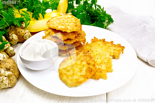 Image of Pancakes of pumpkin with Jerusalem artichoke on light wooden board