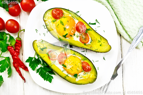 Image of Scrambled eggs with tomatoes in avocado on wooden board top