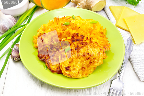 Image of Pancakes of pumpkin with cheese in green plate on light wooden b