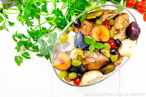 Image of Chicken with fruits and tomatoes in pan on board top