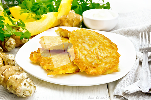 Image of Pancakes of pumpkin with Jerusalem artichoke in plate on white b