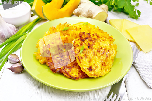 Image of Pancakes of pumpkin with cheese in green plate on wooden board