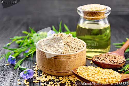 Image of Flour linen in bowl with oil and flowers on dark wooden board