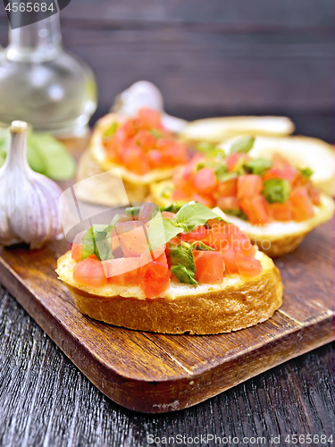 Image of Bruschetta with tomato and spinach on dark board