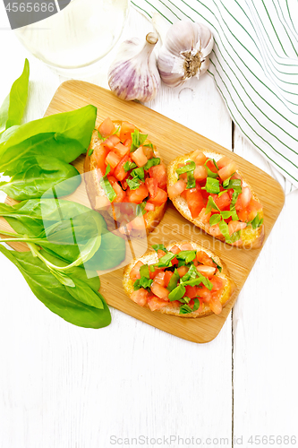 Image of Bruschetta with tomato and spinach on white board top