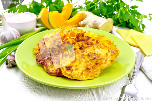 Image of Pancakes of pumpkin with cheese in green plate on board