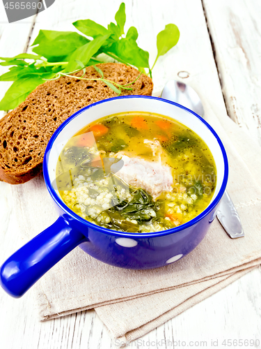 Image of Soup with couscous and spinach in blue bowl on towel