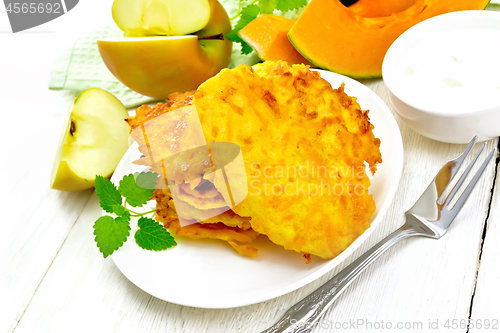 Image of Pancakes of pumpkin with apple in plate on board