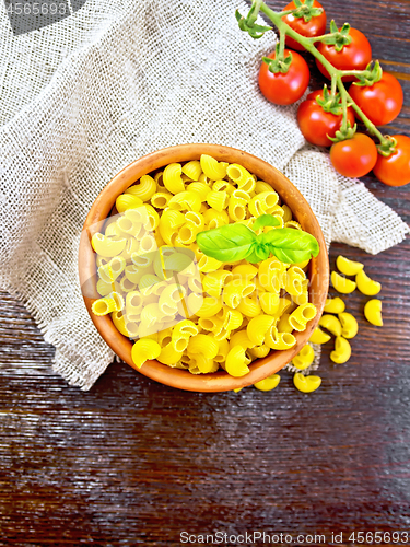 Image of Elbow macaroni in bowl with tomatoes on board top