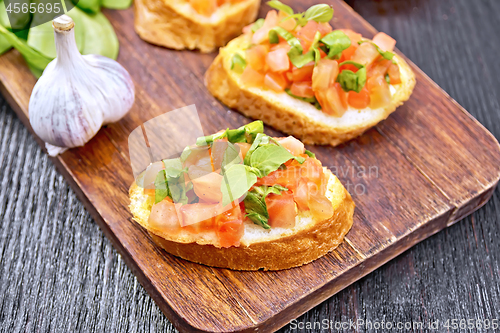 Image of Bruschetta with tomato and spinach on wooden board