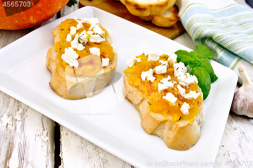 Image of Bruschetta with pumpkin and cheese in plate on light board