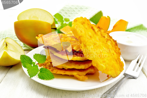 Image of Pancakes of pumpkin with apple in plate on light board