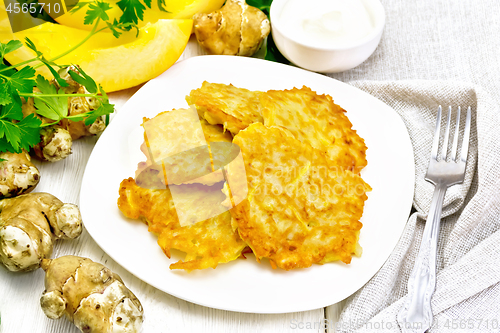 Image of Pancakes of pumpkin with Jerusalem artichoke on wooden board