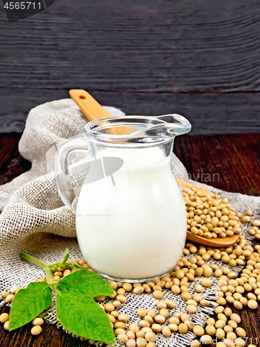 Image of Milk soy in jug with spoon and leaf on board