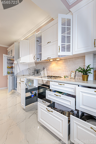 Image of Luxury modern white kitchen interior with open doors and drawers