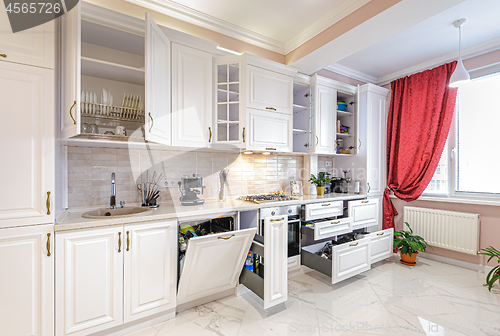 Image of Luxury modern white kitchen interior with open doors and drawers