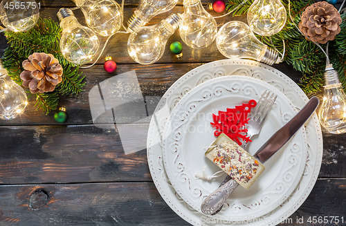 Image of Christmas table setting with fairy lights and fir tree branches.