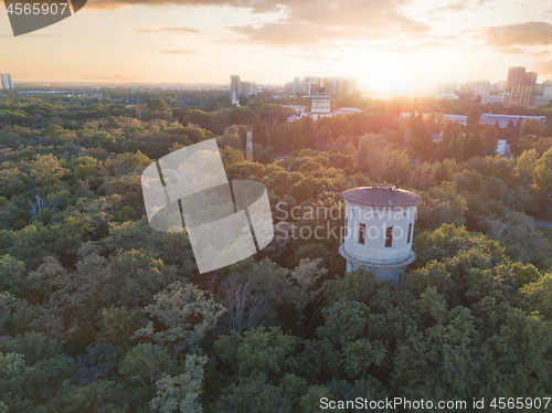 Image of Aerial view of the drone on the green park with a round tower and the city in the distance at sunset