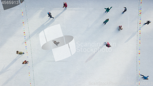 Image of Outdoor ice skating rink with people riding on a winter day. Aerial view from the drone.