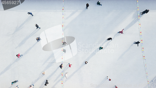 Image of Aerial view of a drone on an open ice rink with people on a winter sunny day.