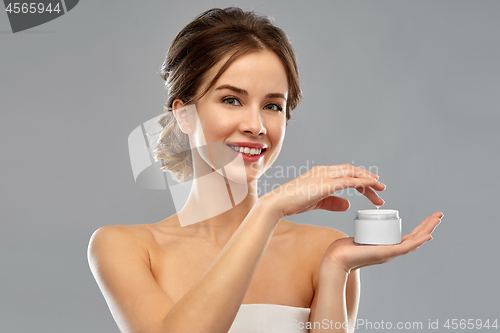 Image of happy young woman holding jar of cream