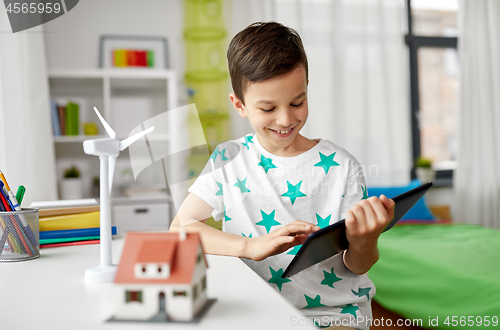 Image of boy with tablet, toy house and wind turbine