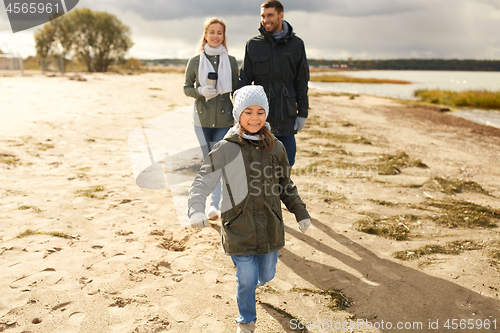 Image of happy family walking along autumn beach
