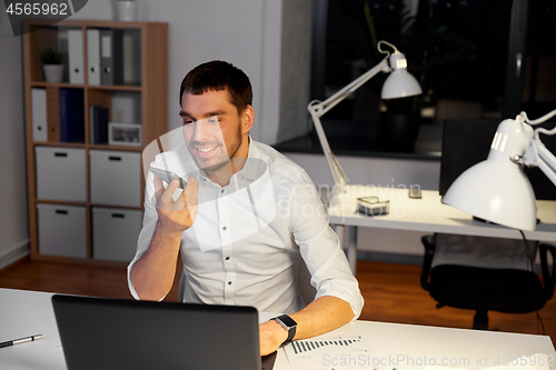 Image of businessman recording voice message on smartphone