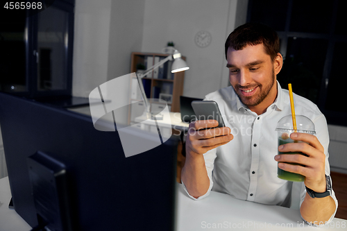 Image of businessman with drink using smartphone at office