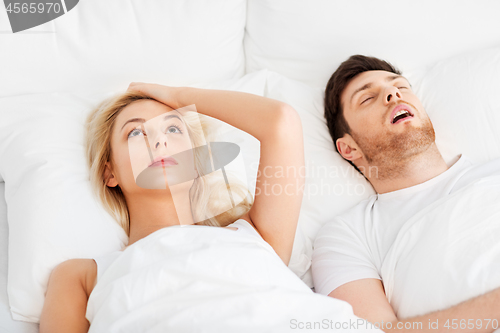 Image of unhappy woman in bed with snoring sleeping man