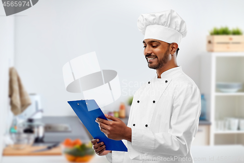 Image of indian chef reading menu on clipboard at kitchen