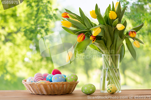 Image of colored easter eggs in basket and flowers