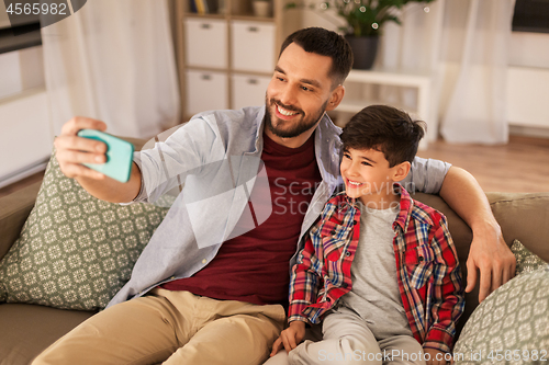Image of father and son taking selfie at home