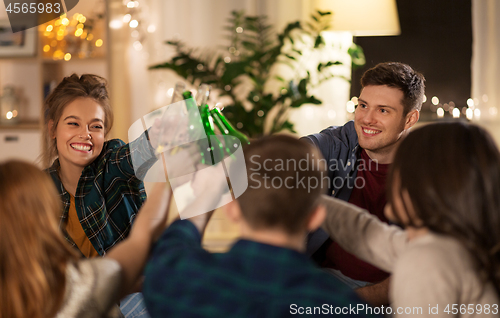 Image of friends clinking drinks at home in evening