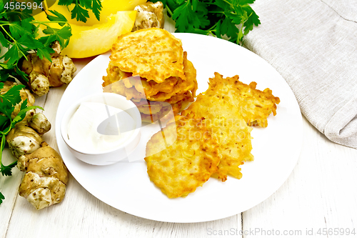 Image of Pancakes of pumpkin with Jerusalem artichoke in plate on board