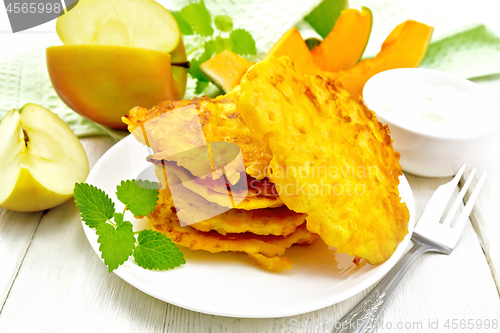 Image of Pancakes of pumpkin with apple in plate on white board