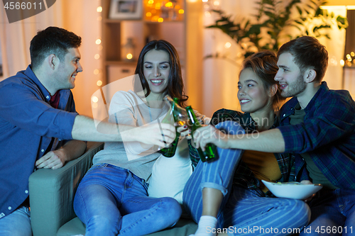 Image of friends clinking drinks at home in evening