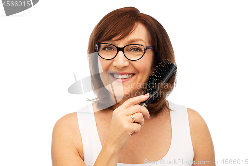 Image of portrait of senior woman in glasses brushing hair